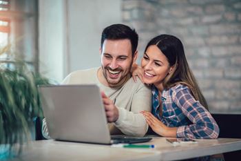 Young couple using laptop on desk at home